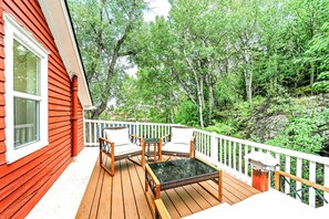 A wooden deck with a white railing, two wicker chairs, and a small table.