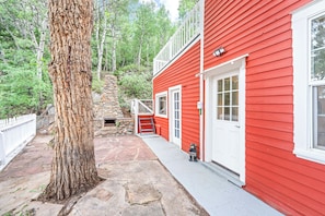 A red building with a stone fireplace, white door, and a welcome sign.
