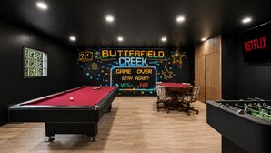 Ett rum med ett biljardbord, ett fotbollsspel och en neonreklamskylt med texten: ”Butterfield Creek – spelet är slut, vill ni stanna kvar igen?”