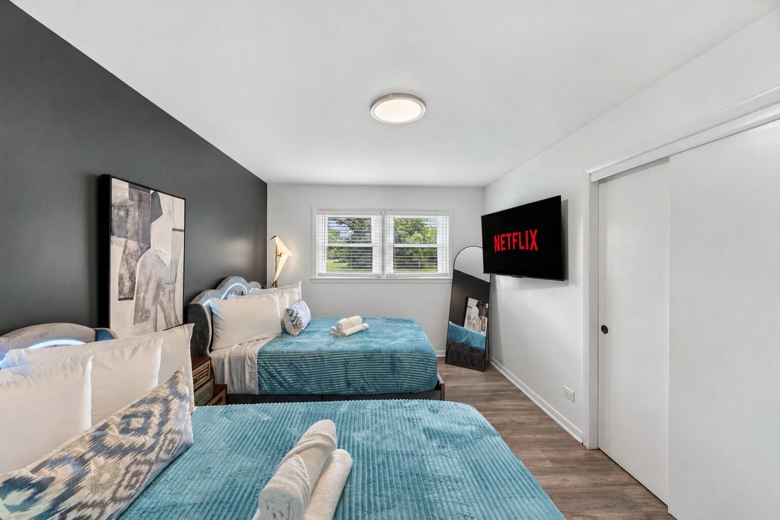 Een slaapkamer met twee bedden, een televisie, een raam en een deur.