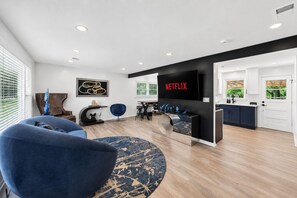Een moderne woonkamer met een blauwe bank, een salontafel en een tv waarop 'NETFLIX' wordt weergegeven.