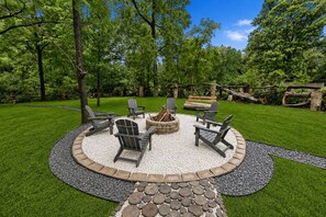 A circular outdoor seating area with Adirondack chairs, a fire pit, and a gravel border. - Creek Retreat on 1 acre / Game Room / Fire Pit (Matteson)