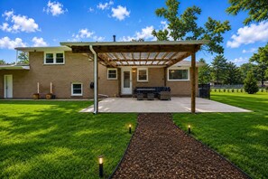 A house with a covered patio, a brick exterior, and a lawn. - Creek Retreat on 1 acre / Game Room / Fire Pit (Matteson)