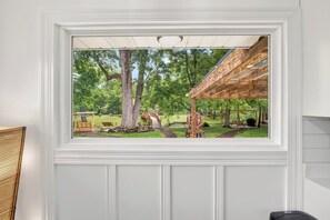 A framed view of a wooden pergola with a swing set and picnic table in a lush green park. - Creek Retreat on 1 acre / Game Room / Fire Pit (Matteson)