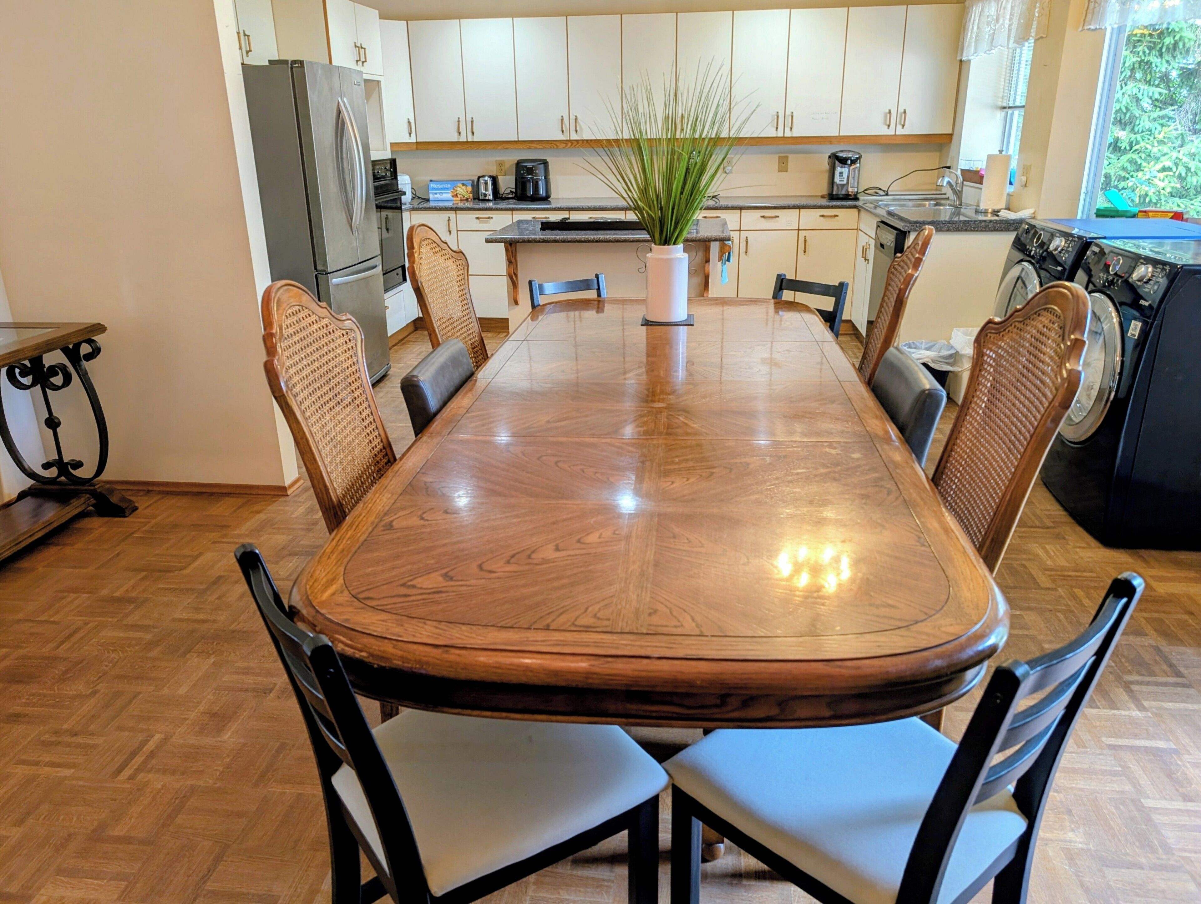 A modern kitchen with a dining table, chairs, and appliances.