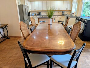 A modern kitchen with a dining table, chairs, and appliances.