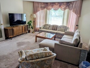 A living room with a sofa set, a television, a coffee table, and a potted plant.