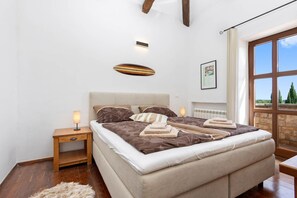 Ein Schlafzimmer mit einem großen Bett, einem Nachttisch, einer Lampe, einer Heizung und einem Fenster mit Blick.