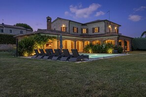 Ein großes Haus mit Swimmingpool, Sitzgelegenheiten im Freien und einer gut beleuchteten Terrasse.
