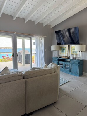 A living room with a sofa, a television, a cabinet, and a sliding glass door leading to an outdoor area.
