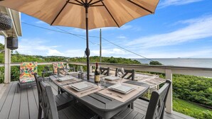 A deck with a table set for dining, overlooking a body of water. - 2 Bedroom Retreat with Ocean Views - Solar & Generator Included (Red Hook Quarter)