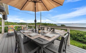 Eine Terrasse mit Esstisch, die auf ein Gewässer blickt.