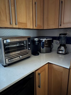A kitchen with a built-in oven, a coffee maker, a blender, and wooden cabinets. - 2 Bedroom Retreat with Ocean Views - Solar & Generator Included (Red Hook Quarter)