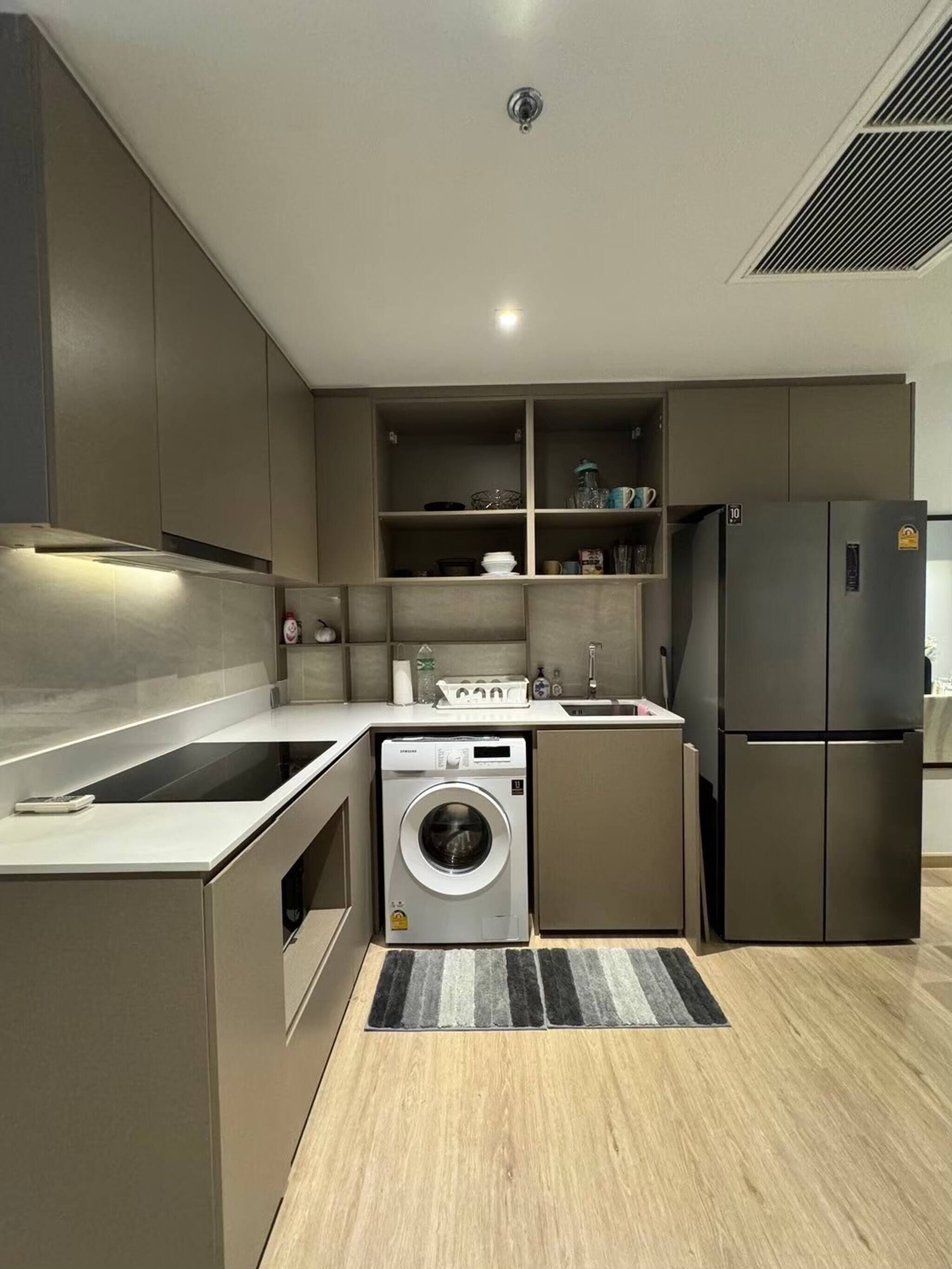 A compact kitchen with a built-in washer and dryer, a refrigerator, and a sink.