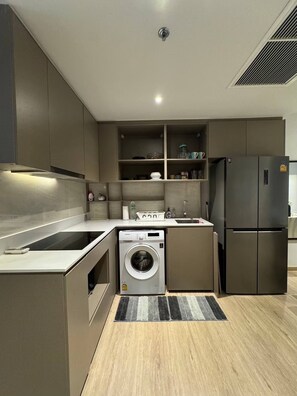 A compact kitchen with a built-in washer and dryer, a refrigerator, and a sink. - 2 Bed Room Luxury I Stunning Sea View & Bath Tub (Pattaya)