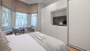 Een hotelkamer met een bed, een bureau met stoelen, een televisie en een kledingkast.