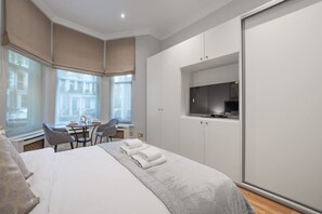 Ein Hotelzimmer mit einem Bett, einem Schreibtisch mit Stühlen, einem Fernseher und einem Kleiderschrank.