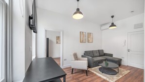 Ein modernes Wohnzimmer mit einer Couch, einem Sessel, einem Couchtisch und einem an der Wand befestigten Fernseher.