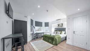 A modern bedroom with a bed, desk, and wardrobe. - Standard Studio in Knightsbridge (London)
