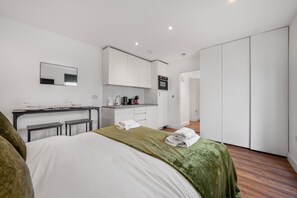 Ein Hotelzimmer mit Bett, einer kleinen Küchenzeile, einem Spiegel und einem Kleiderschrank.
