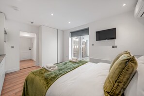 Ein modernes Hotelzimmer mit einem Bett, einem Flachbildfernseher und Blick ins Freie.