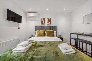 Ein modernes Hotelzimmer mit Bett, Flachbildfernseher, Schreibtisch und Stuhl.
