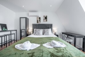 A modern hotel room with a large bed, two bedside tables, a desk, and a chair. - Top Floor Studio With View in Knightsbridge (London)