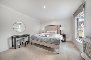 A bedroom with a bed, bedside table, lamp, desk, chair, and a window. - Spacious Knightsbridge Apartment With Balcony (London)