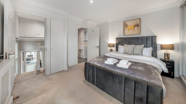 Um quarto moderno com uma cama grande, luminárias de cabeceira e um quadro na parede.
