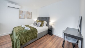 A modern bedroom with a bed, bedside table, and a desk with a chair. - Superior Ground Floor Studio in Knightsbridge (London)