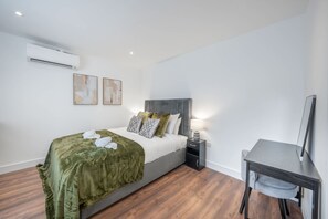 A modern bedroom with a bed, bedside table, and a desk with a chair. - Superior Ground Floor Studio in Knightsbridge (London)