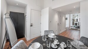 A dining area with a table set for four, a black sofa, and a view of a balcony. - Deluxe Studio Mezzanine With Balcony in Knightsbridge (London)
