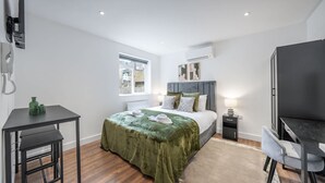 A modern bedroom with a bed, bedside table, and a desk. - Modern Studio in Knightsbridge (London)