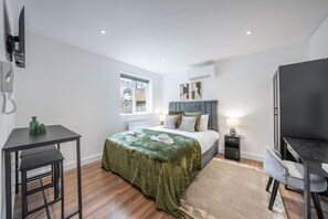 A modern bedroom with a bed, bedside table, and a desk. - Modern Studio in Knightsbridge (London)