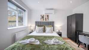 A modern bedroom with a large bed, a desk, and a wardrobe. - Modern Studio in Knightsbridge (London)