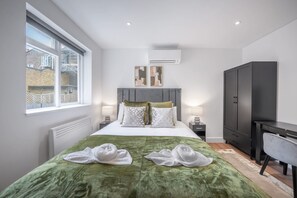 A modern bedroom with a large bed, a desk, and a wardrobe. - Modern Studio in Knightsbridge (London)