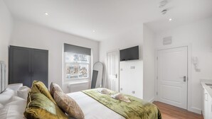 Ein Hotelzimmer mit Bett, Fernseher, Kleiderschrank, Fenster und Tür.