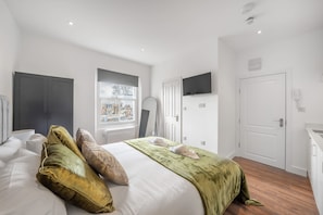 Ein Hotelzimmer mit Bett, Fernseher, Kleiderschrank, Fenster und Tür.