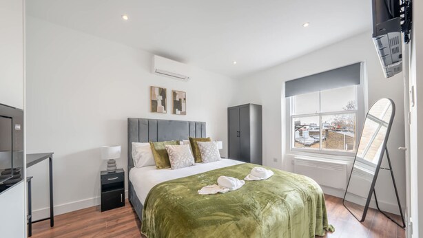 Ein modernes Hotelzimmer mit Bett, Schreibtisch, Kleiderschrank und Fenster mit Blick.