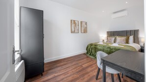 Ein Hotelzimmer mit einem Bett, einem Schreibtisch, einem Stuhl, einem Kleiderschrank und zwei Bildern an der Wand.