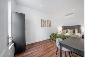Ein Hotelzimmer mit einem Bett, einem Schreibtisch, einem Stuhl, einem Kleiderschrank und zwei Bildern an der Wand.