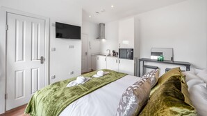 Ein Hotelzimmer mit einem Bett, einem Fernseher, einer Küchenzeile und einer Tür.