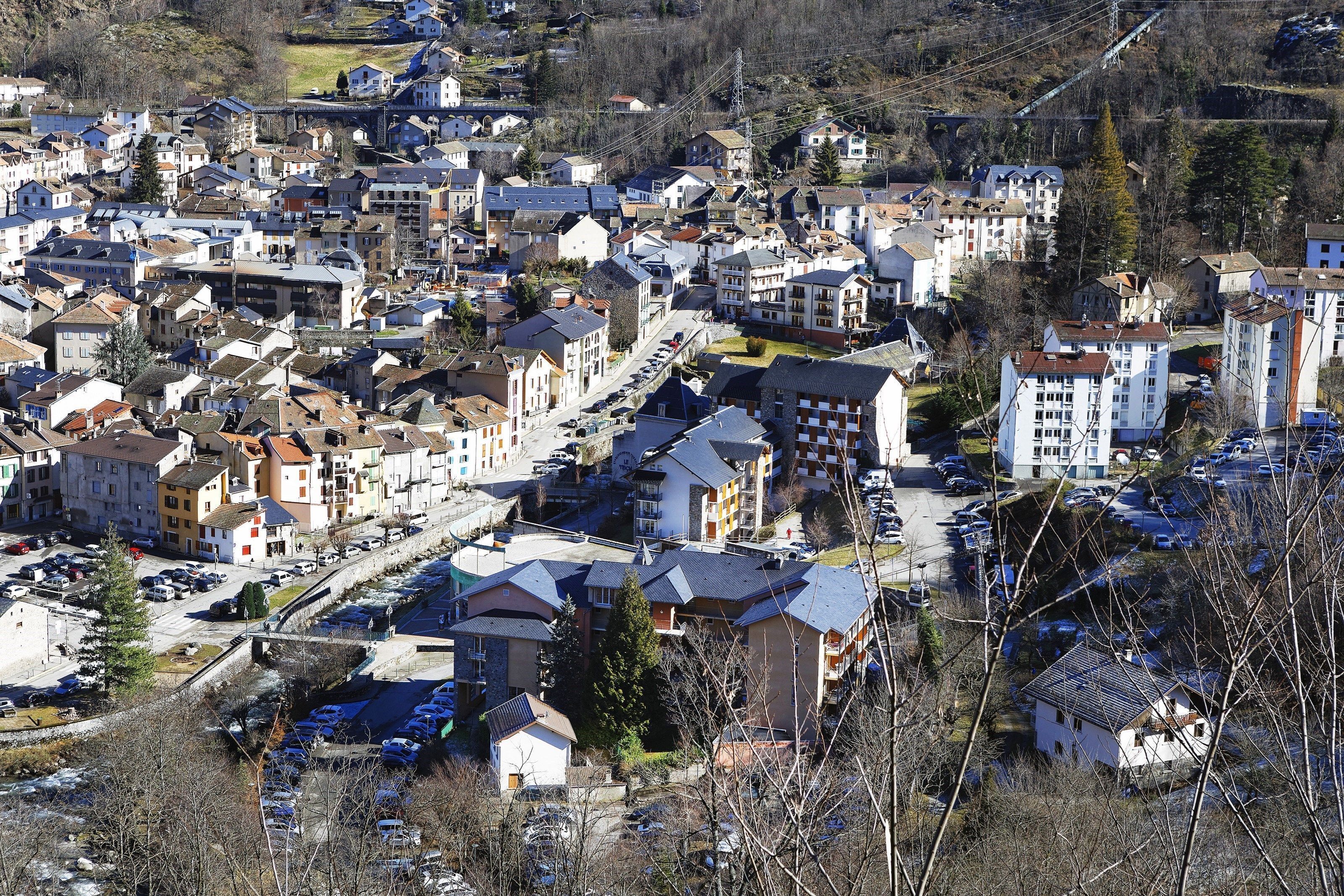 A residential area with multiple apartment buildings, a parking lot, and a bridge in the background.
