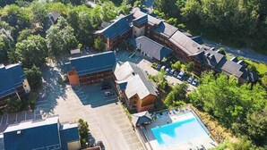 An aerial view of a hotel with multiple buildings, a parking lot, and a swimming pool. - Séjour montagne près du domaine skiable | Piscine (Ax-Les-Thermes)