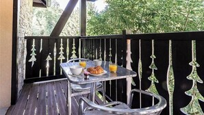 Un balcon avec une table préparée pour le petit-déjeuner, comprenant des croissants et du jus d’orange.