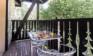 Ein Balkon mit einem Frühstückstisch, komplett mit Croissants und Orangensaft.