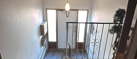A spacious room with a high ceiling, a wooden floor, and a view of a balcony with a railing.