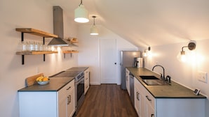 Una cucina moderna con scaffali in legno, forno integrato e lavello in acciaio inossidabile.