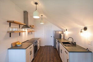 Eine moderne Küche mit Holzböden, einem eingebauten Backofen und einer Edelstahl-Spüle.