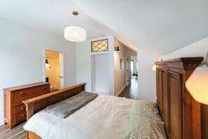 Ein Schlafzimmer mit einem Bett, einer hölzernen Kommode und einer Pendelleuchte.